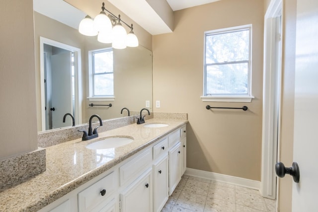 full bath featuring a notable chandelier, a sink, baseboards, and double vanity