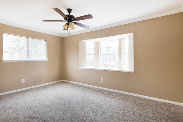 carpeted empty room with ornamental molding, a ceiling fan, and baseboards