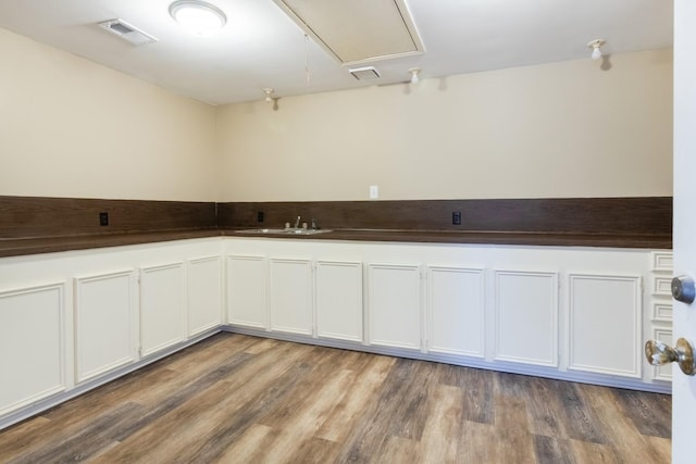 kitchen featuring dark countertops, white cabinets, a sink, and wood finished floors