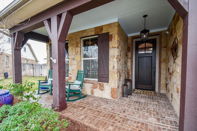 doorway to property featuring stone siding and fence