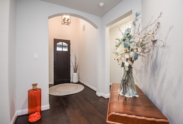 entryway featuring arched walkways, dark wood-type flooring, visible vents, and baseboards