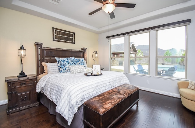 bedroom featuring a raised ceiling, dark wood finished floors, and baseboards