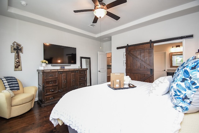 bedroom with a barn door, visible vents, a raised ceiling, a ceiling fan, and dark wood finished floors