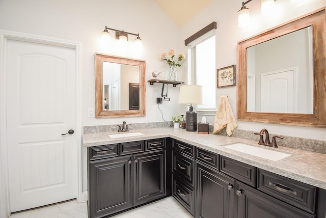 full bathroom with marble finish floor, double vanity, and a sink