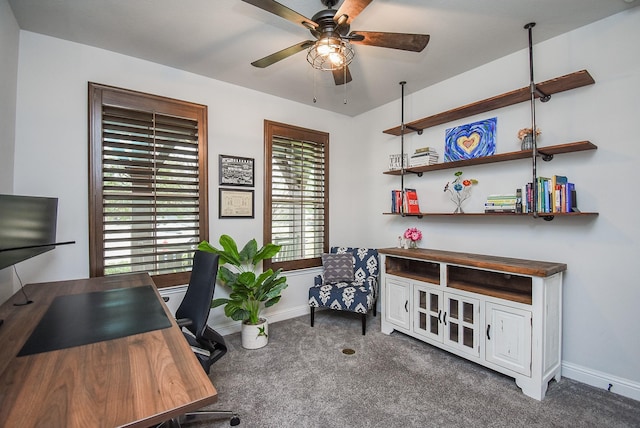 home office with dark colored carpet, ceiling fan, and baseboards