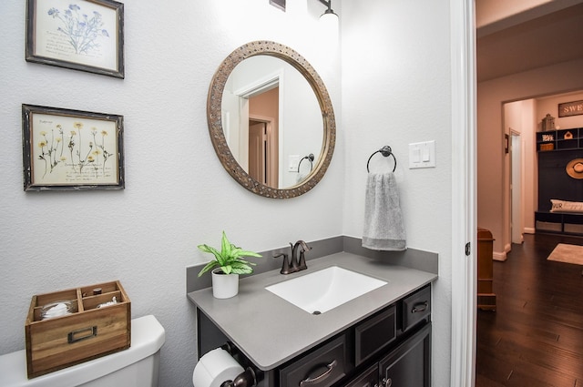 bathroom with toilet, wood finished floors, and vanity