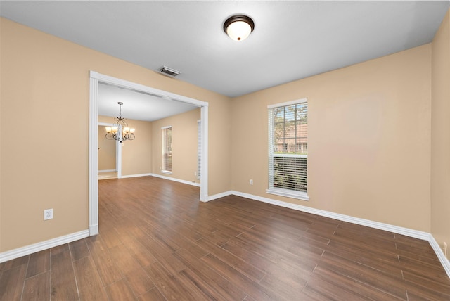 unfurnished room featuring an inviting chandelier, visible vents, baseboards, and dark wood-type flooring