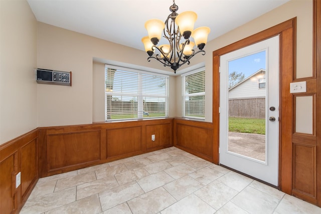 unfurnished dining area with a chandelier and a wainscoted wall