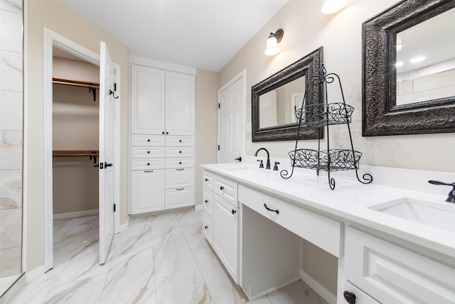 bathroom with a sink, marble finish floor, double vanity, and a walk in closet