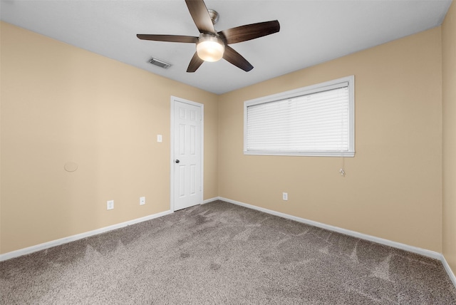 carpeted spare room featuring a ceiling fan, visible vents, and baseboards