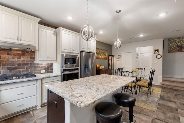 kitchen with white cabinets, a kitchen island, stainless steel appliances, and decorative light fixtures