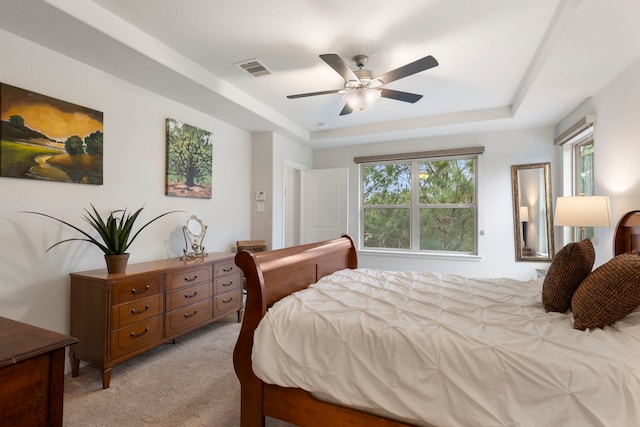 bedroom with ceiling fan, a raised ceiling, visible vents, and light colored carpet