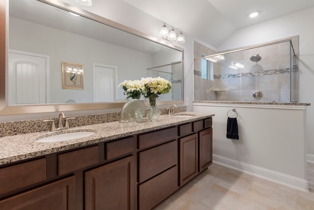 full bath with a tile shower, double vanity, a sink, and baseboards