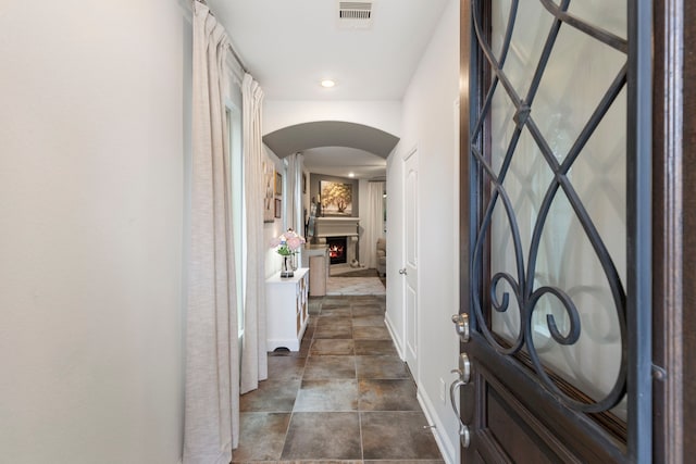 hallway with baseboards, visible vents, arched walkways, and recessed lighting