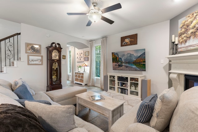 living area featuring stairway, arched walkways, and a ceiling fan