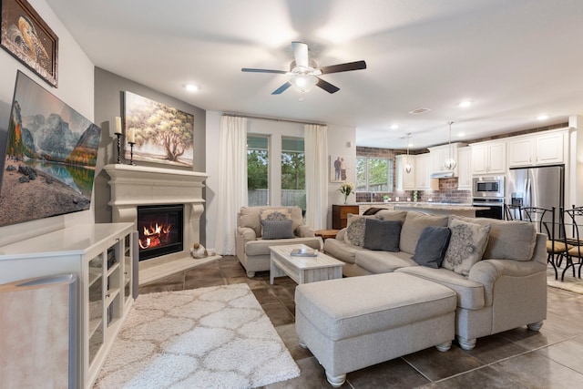 living room featuring recessed lighting, visible vents, a ceiling fan, a glass covered fireplace, and dark tile patterned flooring