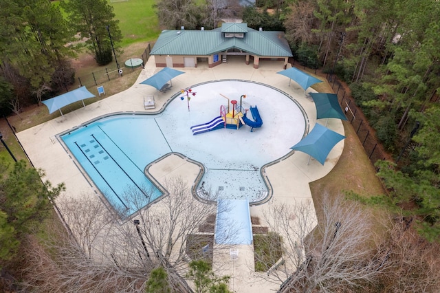 view of swimming pool featuring playground community and fence