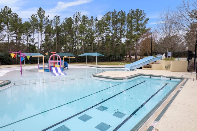 view of pool with playground community, fence, a water play area, and a water slide