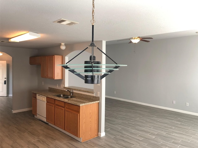 kitchen with arched walkways, brown cabinetry, visible vents, and dishwasher