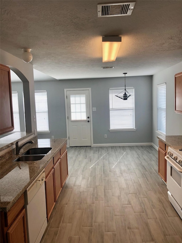 kitchen with stone counters, decorative light fixtures, visible vents, a sink, and white appliances