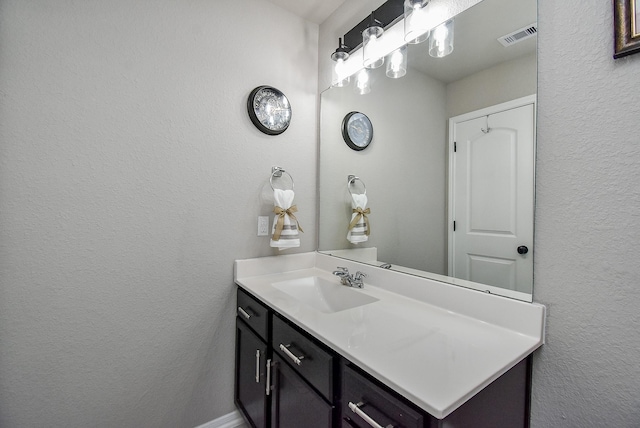 bathroom featuring visible vents, a textured wall, and vanity