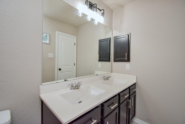 bathroom with a sink, baseboards, and double vanity