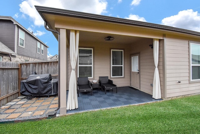 rear view of property featuring a patio, a lawn, and fence