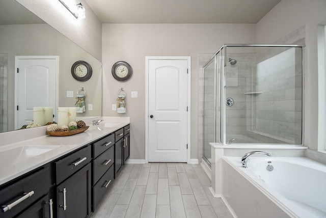 bathroom with a garden tub, double vanity, wood tiled floor, a sink, and a shower stall