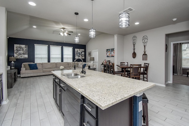 kitchen with a center island with sink, pendant lighting, open floor plan, and a sink