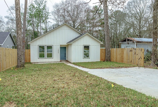 view of front of property with fence, board and batten siding, and a front yard