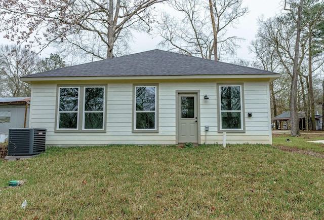 view of front of home featuring roof with shingles, a front lawn, and central air condition unit