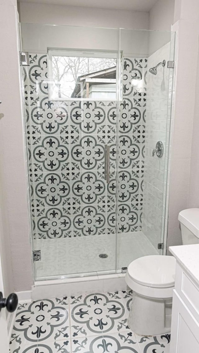 bathroom featuring a stall shower, tile patterned flooring, vanity, and toilet