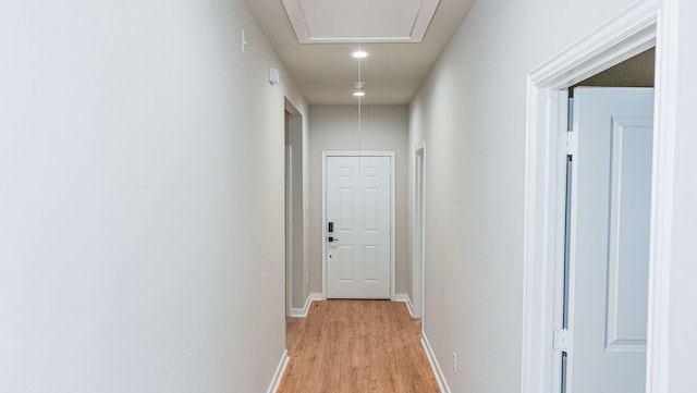 hall with attic access, light wood finished floors, and baseboards