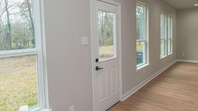 doorway to outside with a healthy amount of sunlight, light wood-style floors, and baseboards