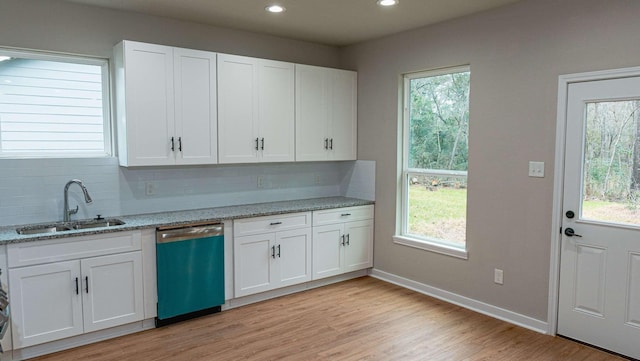 kitchen with a sink, light stone counters, white cabinets, and dishwasher