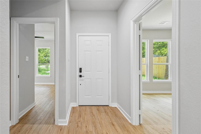 entrance foyer featuring a wealth of natural light, visible vents, light wood-style flooring, and baseboards