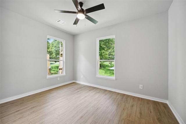 unfurnished room featuring light wood-style flooring, plenty of natural light, visible vents, and baseboards