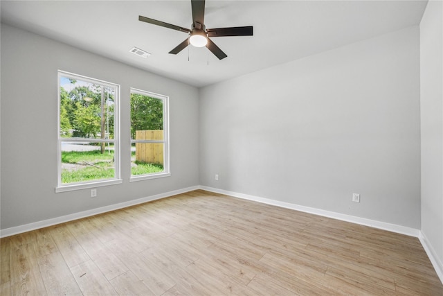 unfurnished room featuring visible vents, light wood-type flooring, a ceiling fan, and baseboards