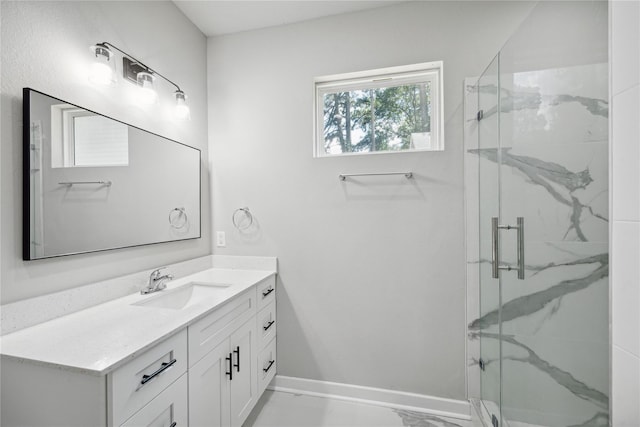 bathroom with marble finish floor, baseboards, vanity, and a marble finish shower