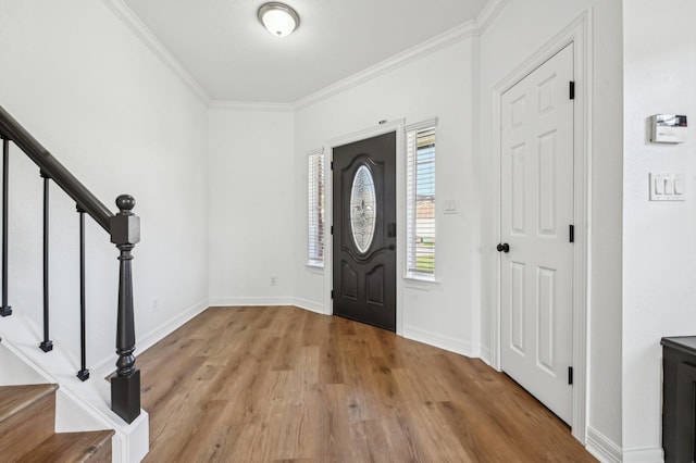 entrance foyer featuring ornamental molding, light wood-type flooring, stairway, and baseboards