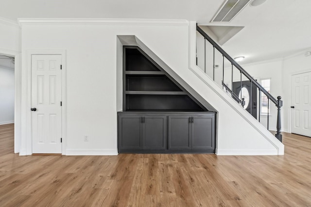 stairs with ornamental molding, visible vents, and wood finished floors