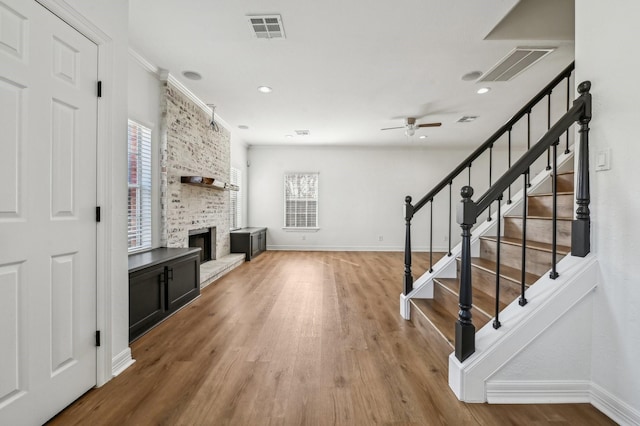 living room featuring a large fireplace, baseboards, visible vents, and wood finished floors