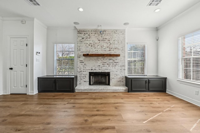 unfurnished living room with a wealth of natural light, a brick fireplace, visible vents, and crown molding