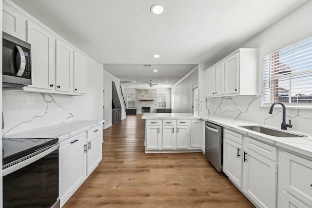 kitchen featuring stainless steel appliances, a peninsula, a sink, white cabinets, and open floor plan