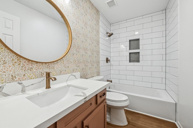 full bathroom with wood finished floors, tub / shower combination, toilet, and wallpapered walls