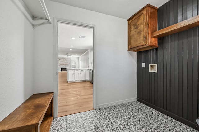 laundry room featuring hookup for a washing machine, a large fireplace, visible vents, and baseboards