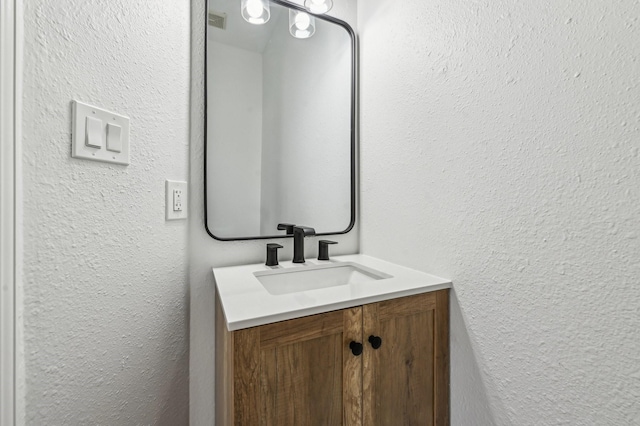 bathroom with a textured wall and vanity