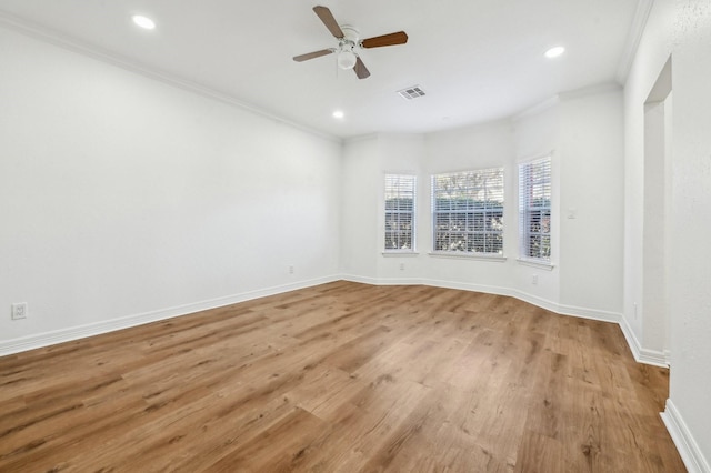 unfurnished room with light wood-style floors, visible vents, crown molding, and baseboards