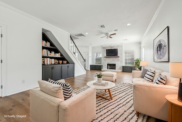 living area featuring visible vents, dark wood finished floors, stairway, crown molding, and a fireplace