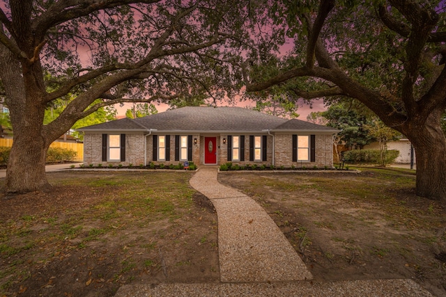 ranch-style home featuring brick siding and a lawn